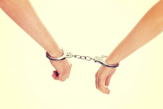 Young beautiful caucasian couple handcuffed.